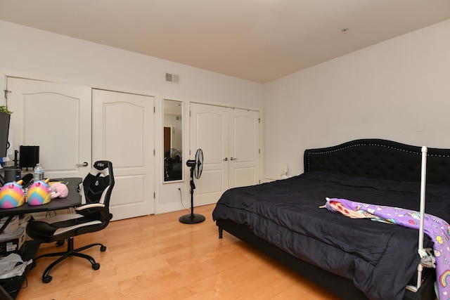 bedroom with light wood-style floors and visible vents