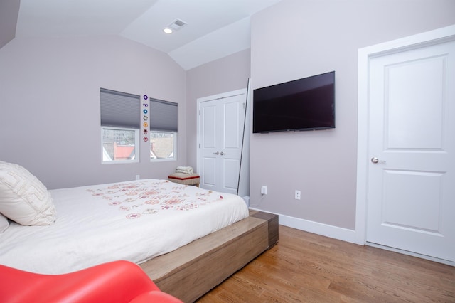 bedroom featuring vaulted ceiling, wood finished floors, a closet, and baseboards