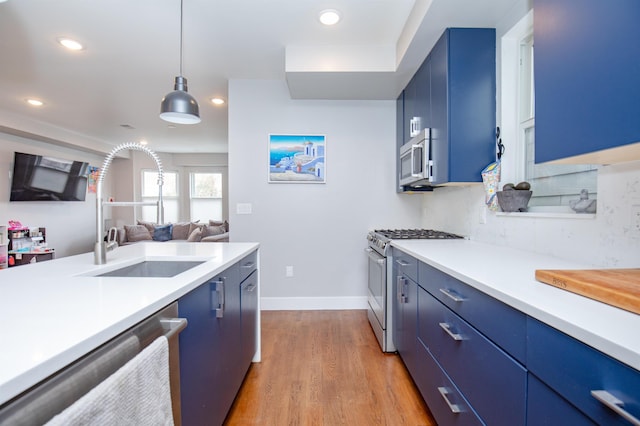 kitchen featuring appliances with stainless steel finishes, recessed lighting, blue cabinets, light countertops, and light wood-type flooring