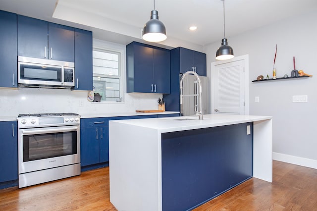 kitchen featuring hanging light fixtures, a sink, stainless steel appliances, light countertops, and blue cabinets