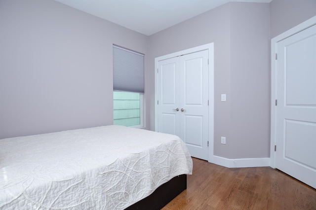 bedroom featuring a closet, wood finished floors, and baseboards