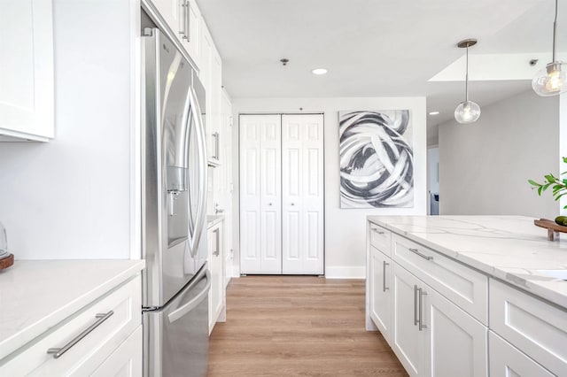 kitchen with white cabinets, decorative light fixtures, stainless steel fridge, and light hardwood / wood-style floors