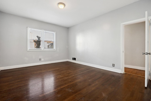 spare room with dark wood-style floors and baseboards