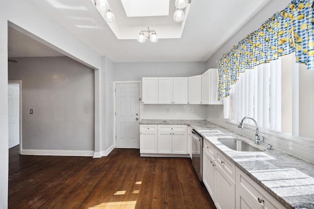 kitchen featuring a skylight, white cabinets, a sink, and light stone countertops