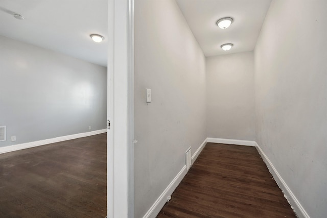 hallway featuring visible vents, baseboards, and dark wood-style flooring