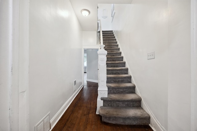 stairs featuring hardwood / wood-style flooring, visible vents, and baseboards