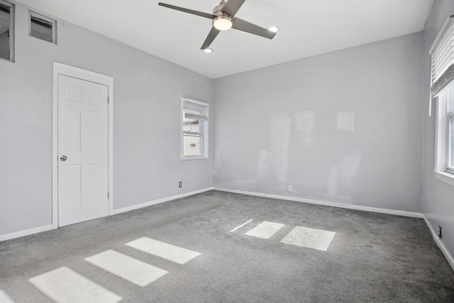 empty room with carpet flooring, ceiling fan, visible vents, and baseboards