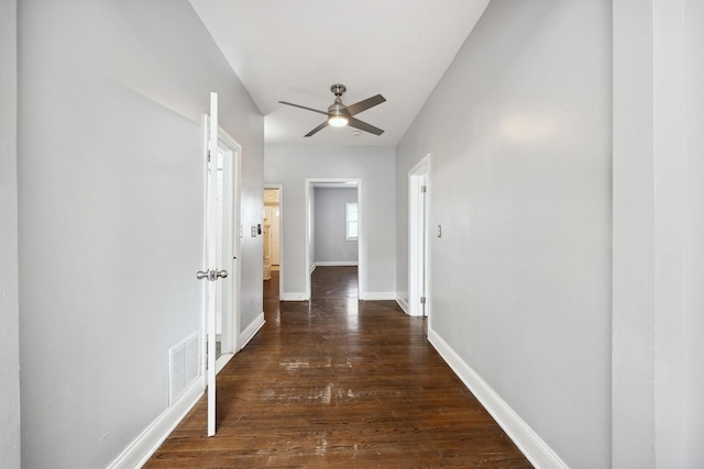 hall featuring dark wood finished floors, visible vents, and baseboards