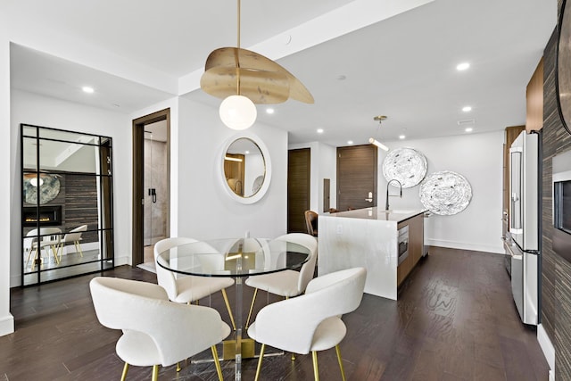 dining space with dark hardwood / wood-style floors, a fireplace, and sink