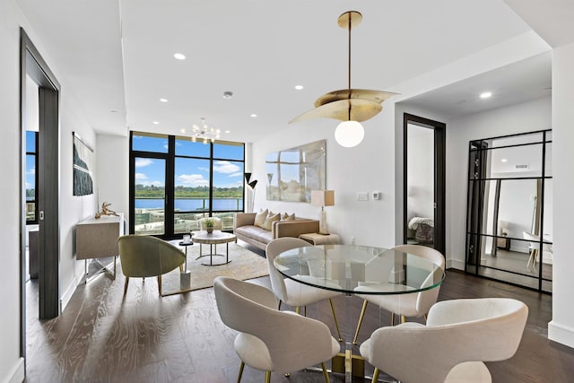 dining area with expansive windows, a water view, dark hardwood / wood-style flooring, and a notable chandelier