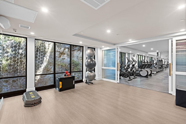 workout area with a wall of windows and light hardwood / wood-style floors