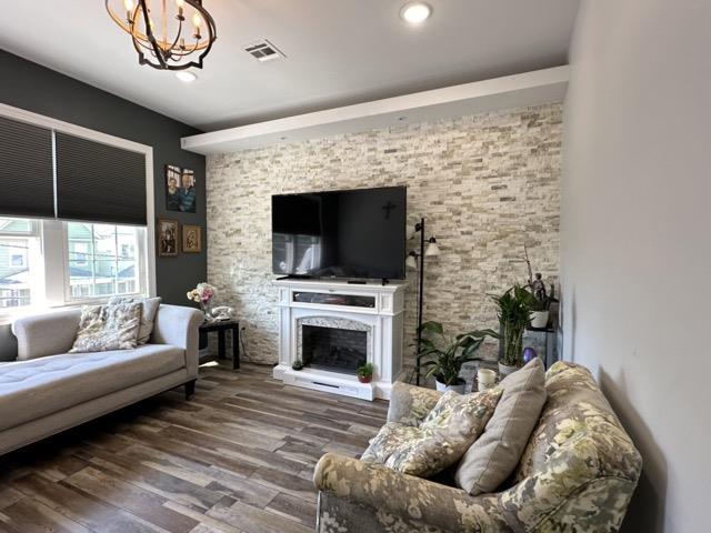 living room with hardwood / wood-style flooring, a fireplace, and an inviting chandelier