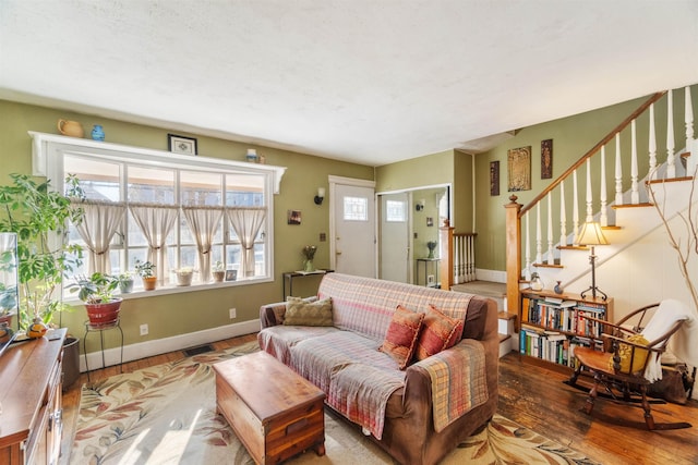 living room featuring stairway, baseboards, visible vents, and hardwood / wood-style floors