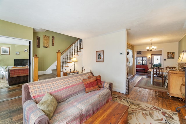 living room with stairs, a notable chandelier, baseboards, and hardwood / wood-style floors