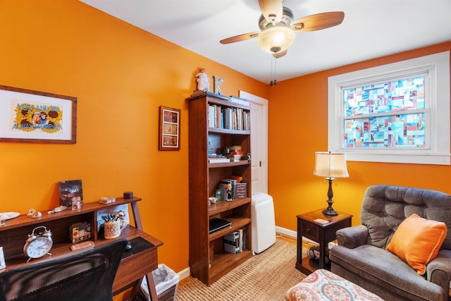 living area featuring baseboards and ceiling fan