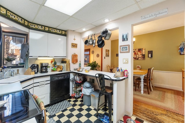 kitchen featuring a drop ceiling, white cabinets, black appliances, and a sink