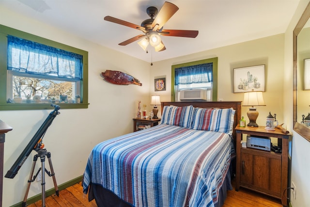 bedroom featuring cooling unit, wood finished floors, baseboards, and ceiling fan