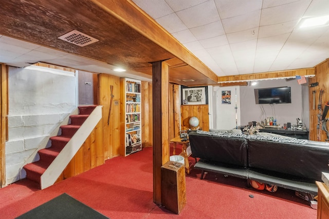 finished basement featuring stairway, visible vents, carpet floors, and wood walls