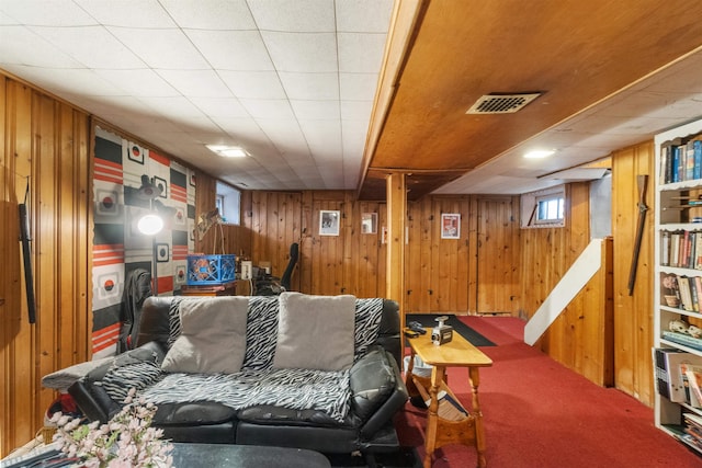 living area featuring visible vents, wooden walls, and carpet floors