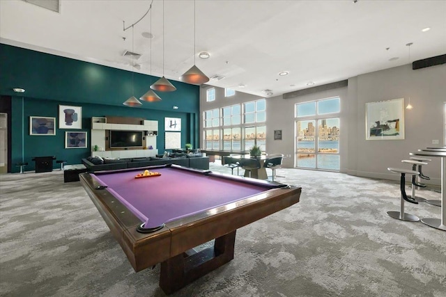 recreation room featuring visible vents, carpet floors, a towering ceiling, and a healthy amount of sunlight