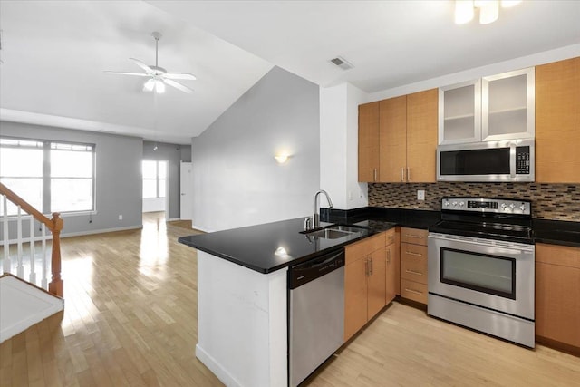 kitchen with visible vents, dark countertops, a peninsula, stainless steel appliances, and a sink