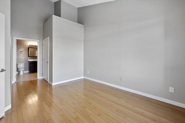 empty room with hardwood / wood-style flooring, a high ceiling, and baseboards