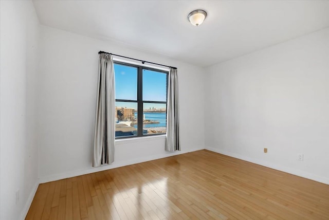 unfurnished room featuring light wood finished floors and baseboards