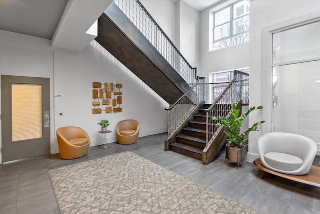 foyer entrance featuring stairs, a high ceiling, and baseboards