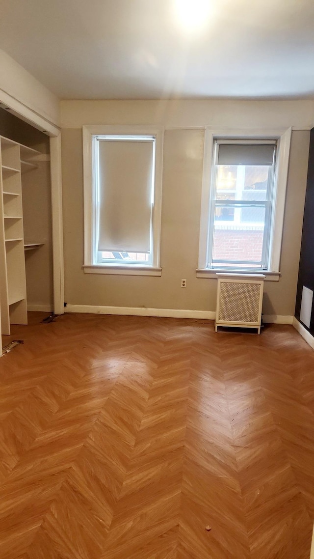 unfurnished bedroom featuring a closet, radiator, and baseboards