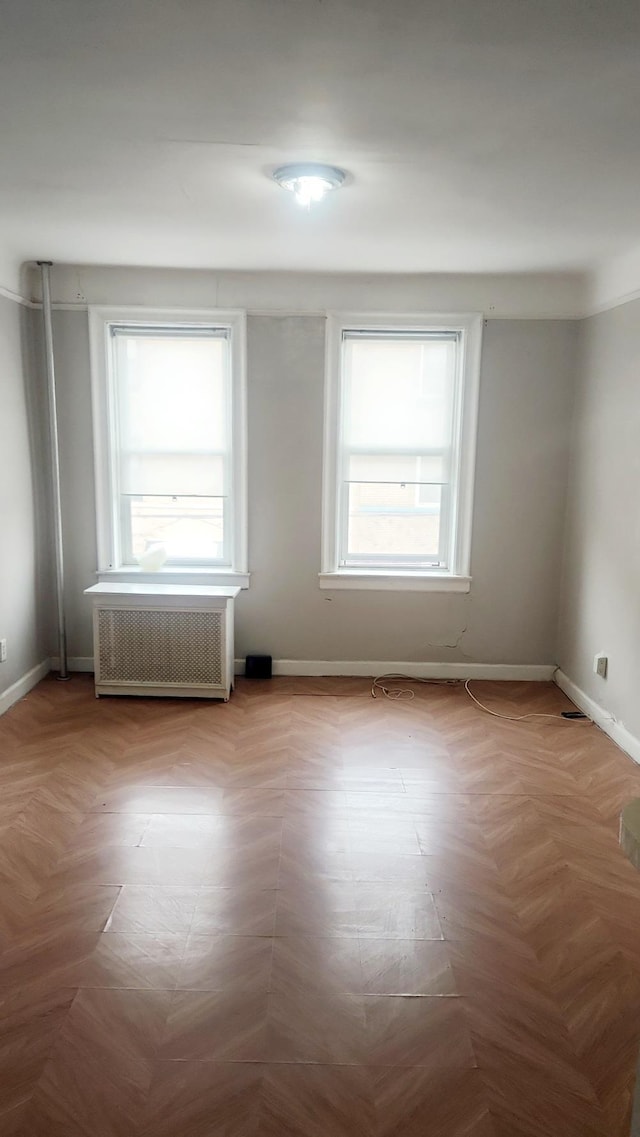 empty room with radiator heating unit and baseboards