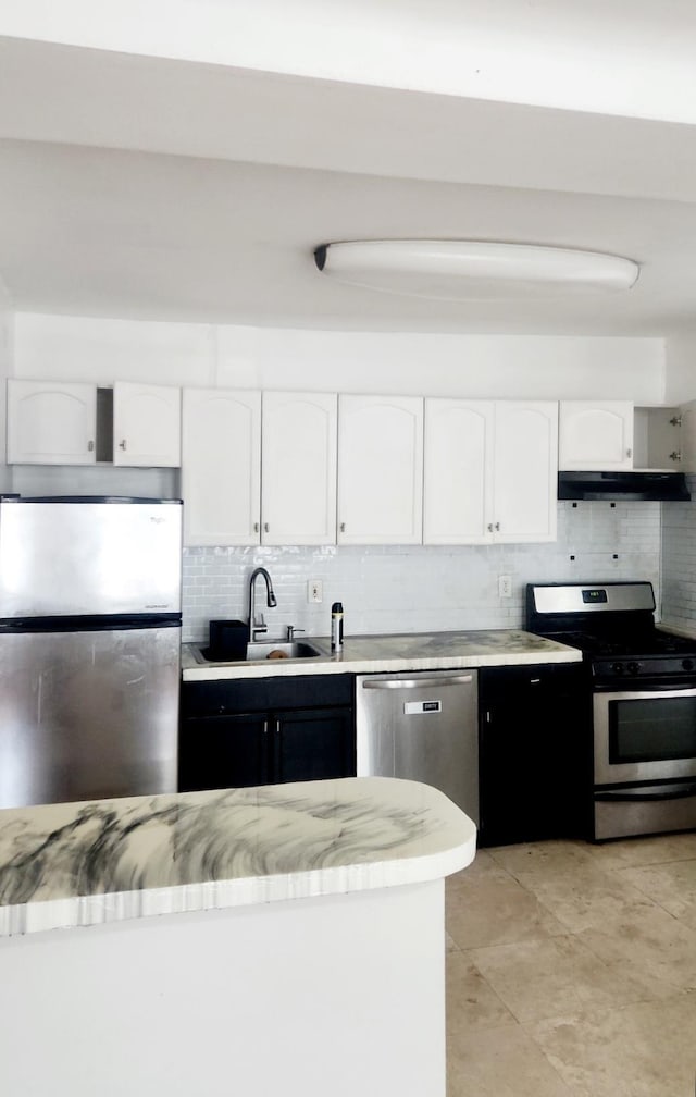 kitchen with decorative backsplash, white cabinets, stainless steel appliances, and a sink