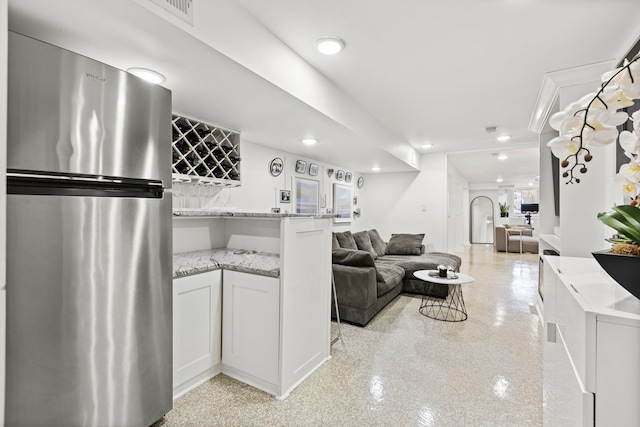 kitchen with white cabinetry, light stone countertops, and stainless steel fridge