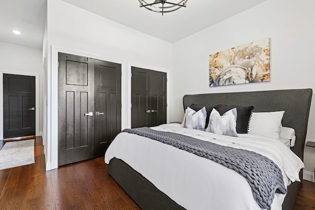 bedroom with dark hardwood / wood-style flooring and multiple closets