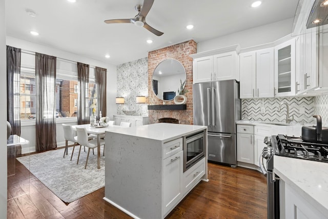 kitchen featuring white cabinets, dark hardwood / wood-style flooring, stainless steel appliances, decorative backsplash, and ceiling fan