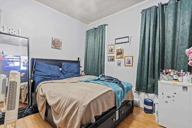 bedroom with white refrigerator, a textured ceiling, light wood-style flooring, and crown molding