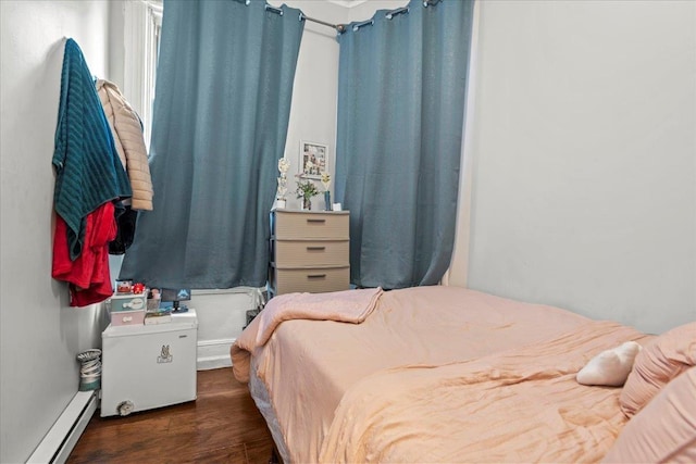 bedroom with baseboard heating and wood finished floors