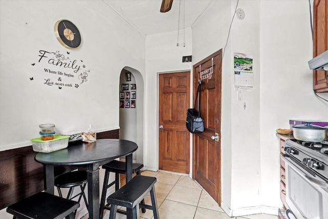 kitchen featuring arched walkways, stainless steel range with gas cooktop, a ceiling fan, and light tile patterned flooring