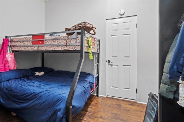 bedroom with baseboards, heating unit, and wood finished floors