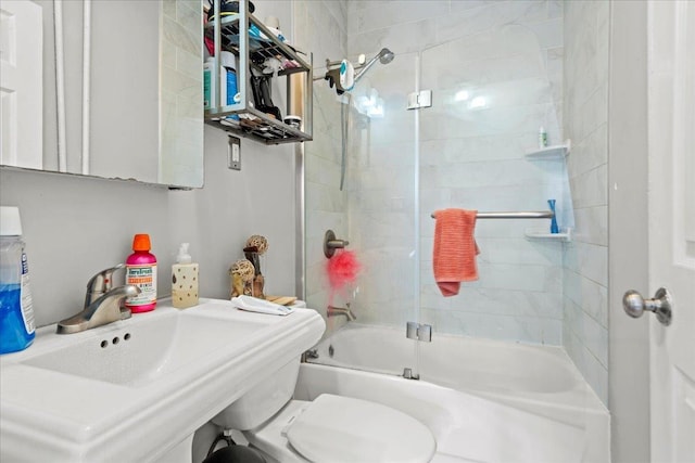 full bathroom with combined bath / shower with glass door, toilet, and a sink