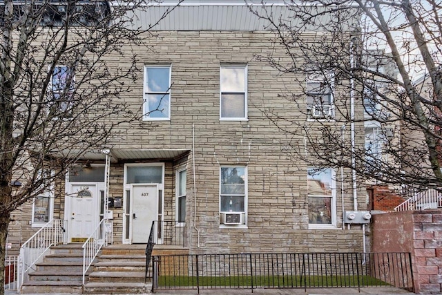 multi unit property with stone siding and a fenced front yard