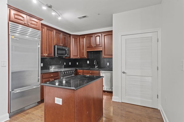 20 Avenue At Port Imperial Unit 102, West New York, NJ 07093 - kitchen with premium appliances, light wood-style floors, tasteful backsplash, a kitchen island, and dark stone counters