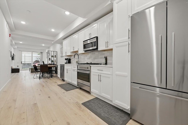 226 Bay St Unit 1, Jersey City, NJ 07302 - kitchen featuring appliances with stainless steel finishes, light wood-style flooring, white cabinetry, decorative backsplash, and light countertops