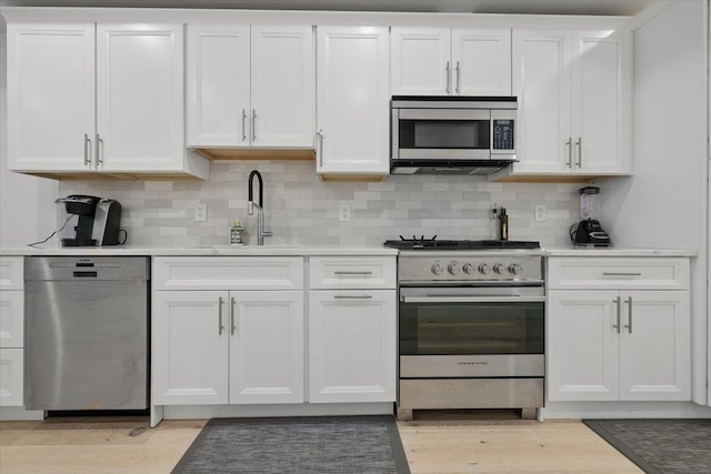 226 Bay St Unit 1, Jersey City, NJ 07302 - kitchen with appliances with stainless steel finishes, a sink, white cabinetry, and light countertops