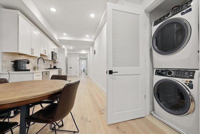 226 Bay St Unit 1, Jersey City, NJ 07302 - laundry room featuring estacked washer and dryer, light wood finished floors, recessed lighting, and baseboards