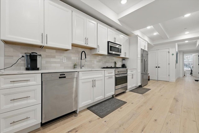 226 Bay St Unit 1, Jersey City, NJ 07302 - kitchen with premium appliances, tasteful backsplash, white cabinets, light countertops, and light wood-style flooring