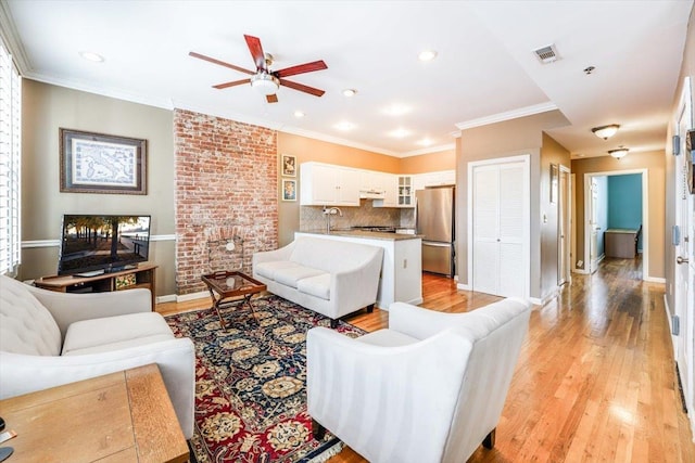 living room featuring ceiling fan, crown molding, sink, and light hardwood / wood-style flooring