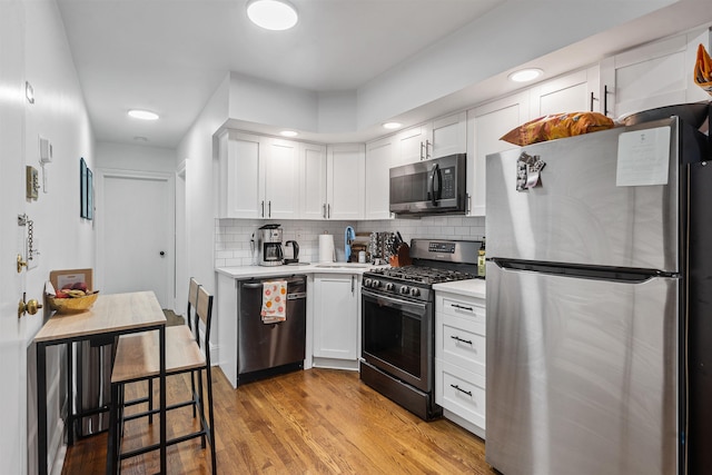 422 Grand St Unit 4, Hoboken, NJ 07030 - kitchen featuring appliances with stainless steel finishes, light countertops, white cabinetry, decorative backsplash, and light wood-style floors