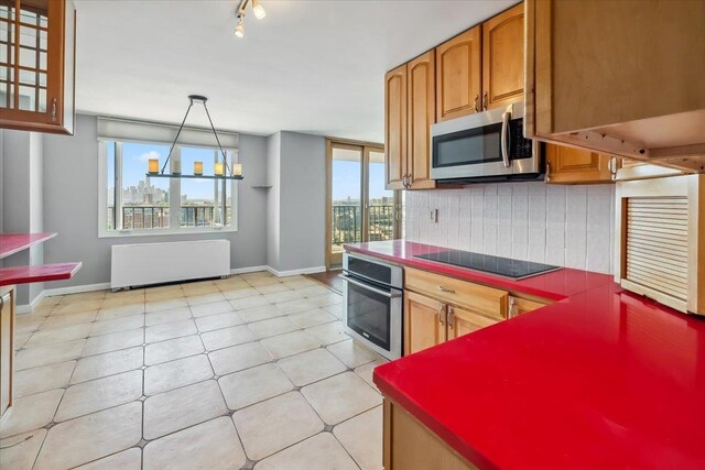 380 Mountain Rd Unit 213, Union City, NJ 07087 - kitchen featuring stainless steel appliances, radiator heating unit, backsplash, brown cabinetry, and hanging light fixtures