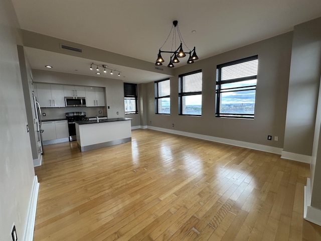 4 Beacon Way Unit 1001, Jersey City, NJ 07304 - kitchen featuring stainless steel appliances, dark countertops, open floor plan, light wood-style flooring, and white cabinetry
