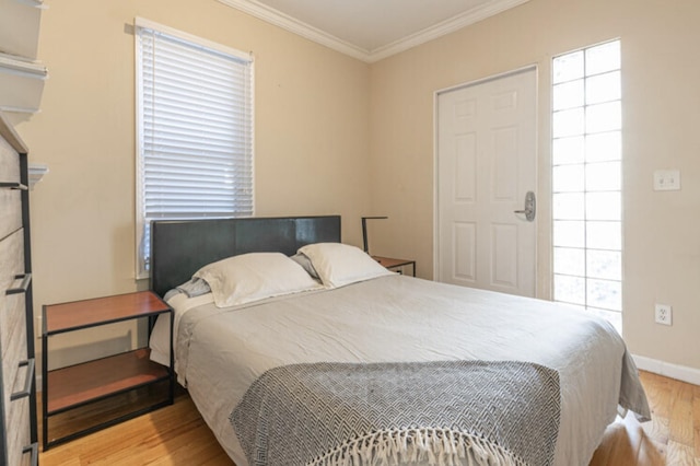 bedroom featuring ornamental molding, baseboards, and wood finished floors